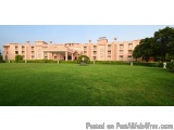 The image shows a large, luxurious building with a large lawn in front of it. The building is a two-story structure with a fl...