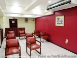 The image shows a waiting area in a hotel lobby. The walls are painted in a bright red color and there is an air conditioning...