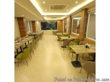 The image shows a modern and spacious dining area in a restaurant. The floor is made of light-colored tiles and the walls are...