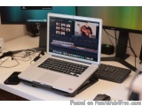 The image shows a laptop computer sitting on top of a desk next to two computer monitors. The laptop is open and the screen i...
