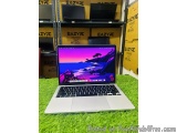 The image shows a laptop computer sitting on a green artificial grass surface. The laptop is silver in color and has a black...