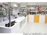 The image shows the interior of a pharmacy. The pharmacy has a white counter with a black countertop and a yellow countertop....