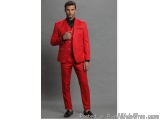 The image shows a young man wearing a red suit. He is standing in front of a plain grey background and is posing with his han...