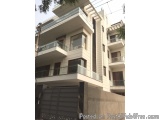 The image shows a modern two-storey building with a white exterior and a black gate in front of it. The building has multiple...