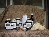 The image shows a collection of various items on a brown and gold patterned couch. There are several bottles of different siz...