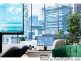The image shows a modern office space with a large window that offers a view of the city skyline. On the left side of the ima...