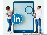 The image shows a man and a woman standing next to a large blue tablet with the LinkedIn logo on it. The tablet is open and t...