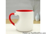 The image is of a white ceramic mug with a red handle. The mug has a heart-shaped design on the side and a handle on the top....