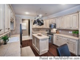 This image is of a modern kitchen with white cabinets and a large island in the center. The kitchen has a large window above...
