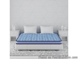 The image shows a modern bedroom with a white bed in the center. The bed has a blue mattress with a geometric pattern on it....