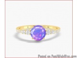 The image is of a gold ring with a large, oval-shaped gemstone in the center. The gemstone is a deep purple color and appears...