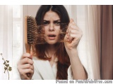 The image shows a young woman holding a wooden hairbrush in front of her face. She is holding the brush with both hands and a...