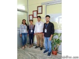 The image shows four people standing in a room with a marble floor and a large window in the background. There are three fram...