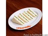 The image shows a white plate with six slices of bread arranged in a diagonal line on it. The bread appears to be a sandwich,...