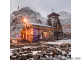 The image shows a Hindu temple in a mountainous area. The temple is made of stone and has a small shrine in front of it. The...