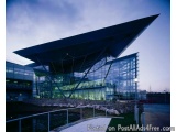 The image shows a modern building with a unique architectural design. The building has a large triangular roof with a triangu...