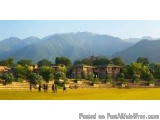 The image shows a beautiful landscape of a rural area with a mountain range in the background. The sky is blue and clear, and...