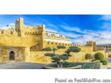 The image shows a beautiful landscape of a castle with a blue sky and white clouds in the background. The castle is made of s...
