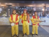 The image shows three young men dressed in traditional Indian attire. They are standing in front of a banner that reads "Kili...