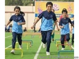 The image shows a group of children running on a track. There are three children in the foreground, two girls and one boy, al...