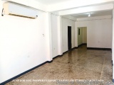 The image shows an empty room with white walls and a tiled floor. On the left side of the image, there is an air conditioning...