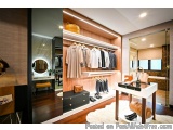 The image shows a modern and luxurious walk-in closet with a wooden wardrobe and a white table. The wardrobe has a wooden she...