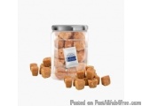 The image shows a glass jar with a metal lid. The jar is filled with small cubes of food, which appear to be peanut butter or...