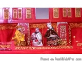 The image shows a stage set up for a performance. The stage is decorated with red and gold accents and has a red curtain in t...