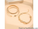 The image shows two bracelets on a beige background. The bracelets are made of gold and have a chain-like design. The first b...