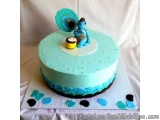 The image is of a round cake with a light blue frosting. The cake is placed on a white surface with small blue and black polk...