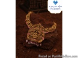 The image shows a traditional Indian necklace made of gold. The necklace is displayed on a piece of soil, with a blurred back...