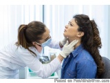 The image shows a young woman sitting in a chair with her eyes closed, while a dentist is examining her neck. The dentist is...