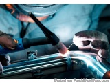 The image shows a person's hands holding a welding torch and working on a metal pipe. The person is wearing a blue shirt and...