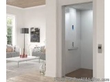 The image shows a modern living room with a large window on the left side. The room has white walls and a wooden ceiling. On...