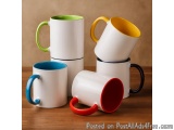 The image shows a stack of four ceramic mugs on a wooden surface. The mugs are of different colors - white, green, yellow, bl...