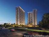 The image shows two tall, modern high-rise buildings on a street at dusk. The buildings are made of glass and steel, with a u...