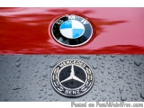 The image is a close-up of the emblem of a red car. The emblem is circular in shape and has the letters "BMW" in the center,...