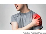 The image shows a young man wearing a grey t-shirt, holding his elbow in pain. He appears to be in discomfort, with his mouth...