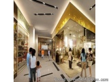 The image is a 3D rendering of a shopping mall. The mall has a modern design with a high ceiling and a large yellow sign that...