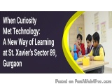 The image shows a group of students in a classroom, sitting at a desk and working together on a project. They are wearing sch...