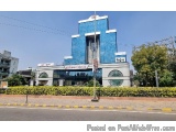 The image shows a modern building with a blue and white color scheme. The building has a unique design with a curved roof and...