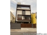 The image shows a modern two-storey building with a flat roof. The building is located on a street with other buildings visib...
