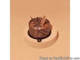 The image is of a round cake stand with a chocolate cake on top. The cake is made of a dark brown cake with a striped pattern...
