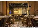 The image shows the interior of a modern restaurant with wooden walls and a large window. The restaurant has a high ceiling w...