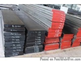 The image shows a stack of black and red metal sheets in a warehouse. The sheets are stacked on top of each other and appear...