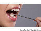 The image shows a close-up of a person's mouth with their mouth open, revealing their teeth. The person is holding a dental t...