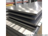 The image shows a stack of four metal sheets in a warehouse. The sheets are arranged in a horizontal manner, with the top she...