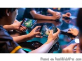 The image shows a group of people sitting around a table, playing a video game on their smartphones. The focus of the image i...