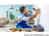 In this image, we can see a young man wearing a blue uniform and overalls, working on a security camera mounted on a white wa...