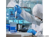 The image shows a person wearing a white protective suit, a face mask, and blue gloves, working in a laboratory. The person i...